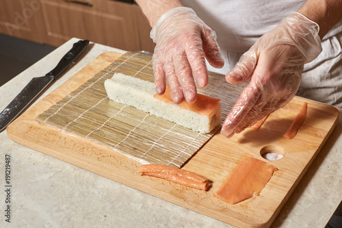Chef making sushi. Preparing rolls with salmon