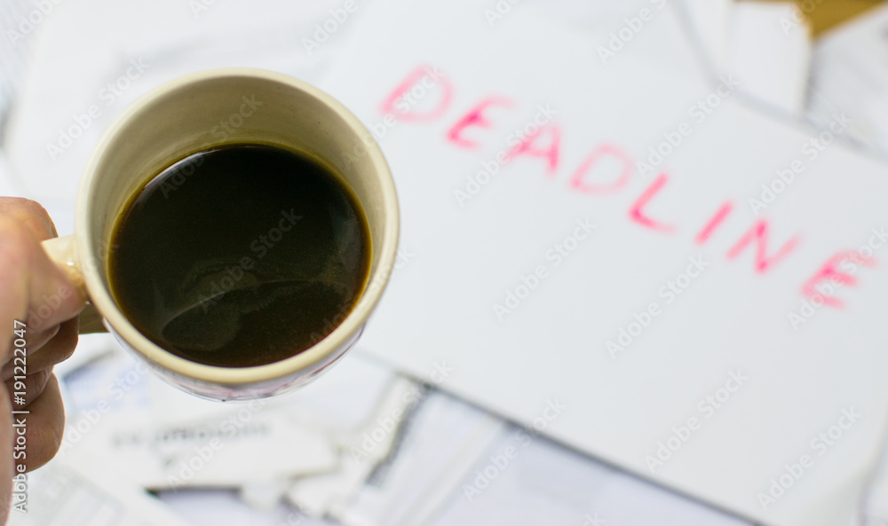Procrastination concept: Drink coffee, when you can already see deadline. A cup of coffee on the background of the inscription deadline on the scattered papers. Procrastination concept: Drink coffee, when you can already see deadline. A cup of coffee on the background of the inscription deadline on the scattered papers.