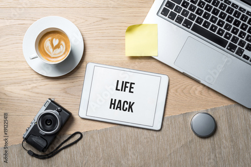 Life hack written on tablet in office as flatlay photo