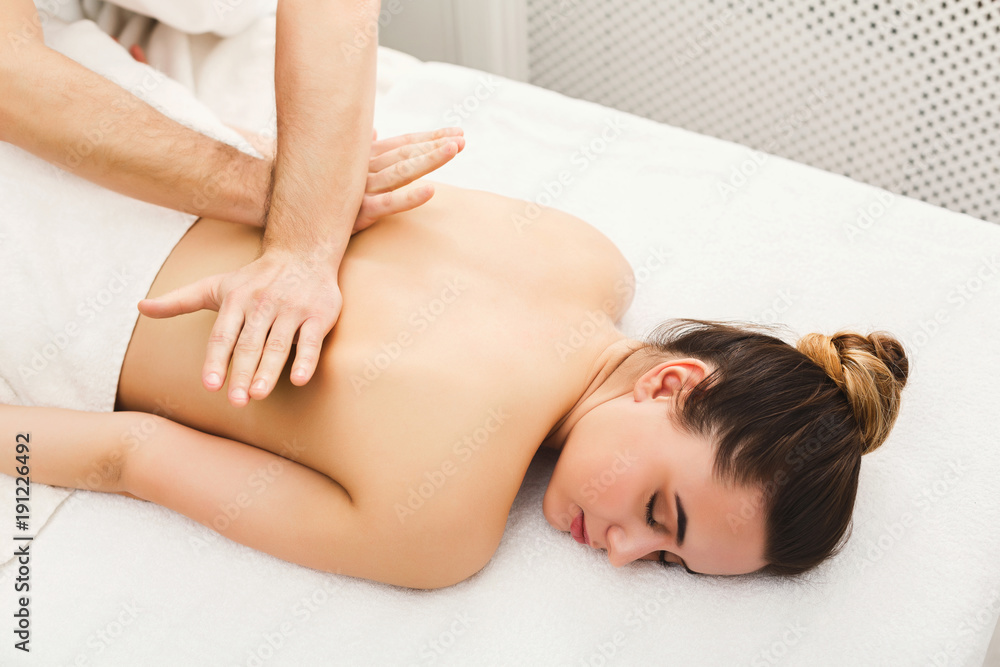 Closeup of hands massaging female shoulders and back Closeup of hands massaging female shoulders and back