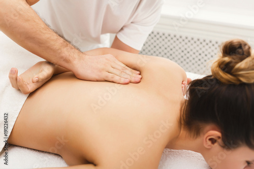 Closeup of hands massaging female shoulders and back