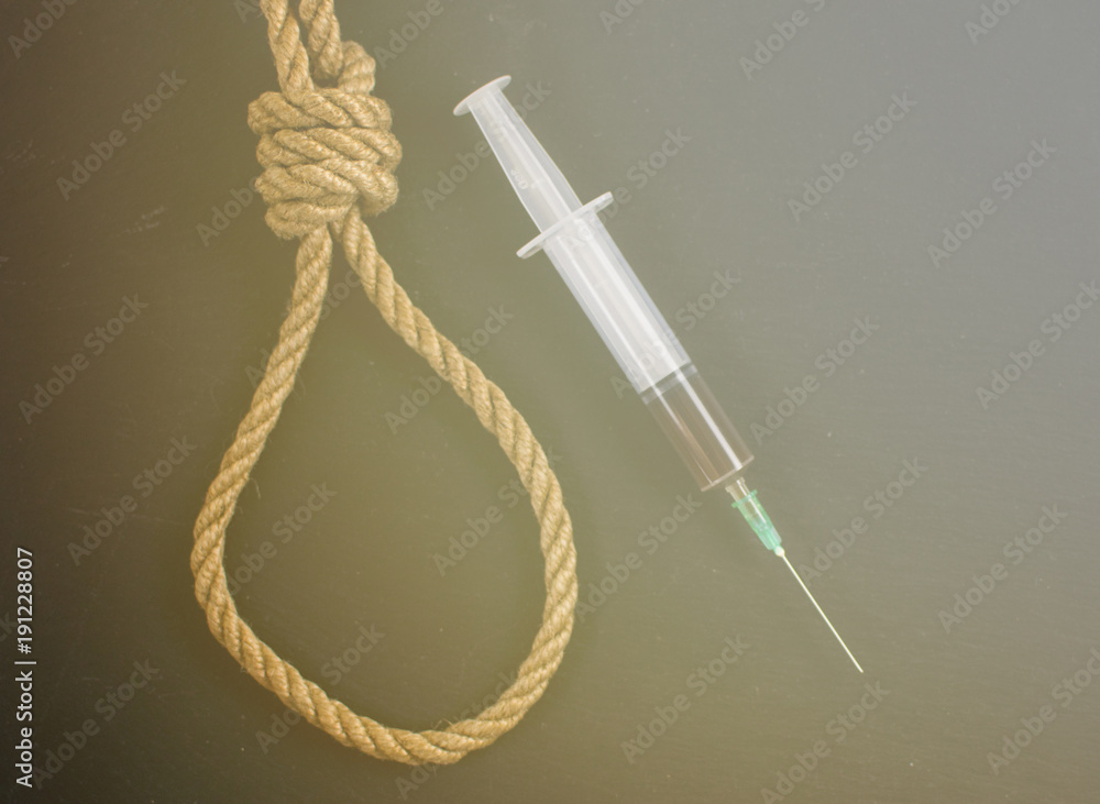 Drugs are suicide. A hinge for the gallows and a syringe with heroin on a black background.