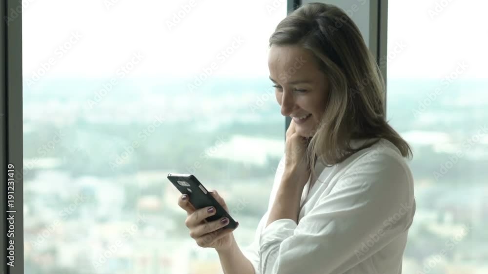 Happy woman texting on smartphone standing by window at home
Happy woman texting on smartphone standing by window at home