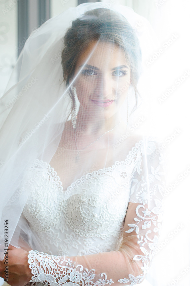 Beautiful bride in white dress posing under curtain Beautiful bride in white dress posing under curtain