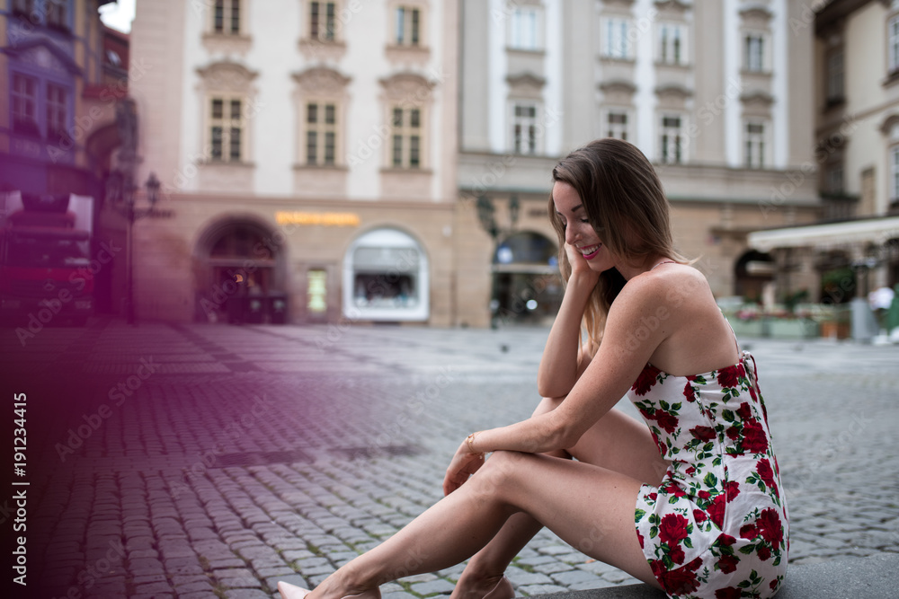 Woman sitting in a flower dress at old town square in prague, czech replic Woman sitting in a flower dress at old town square in prague, czech replic