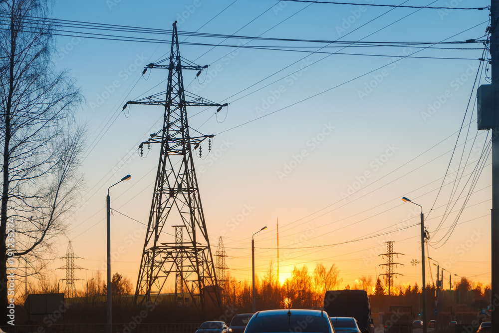 High voltage power lines in an urban environment on the background of sunset
