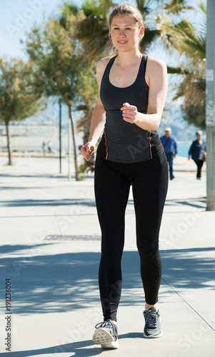 Sporty woman running along embankment