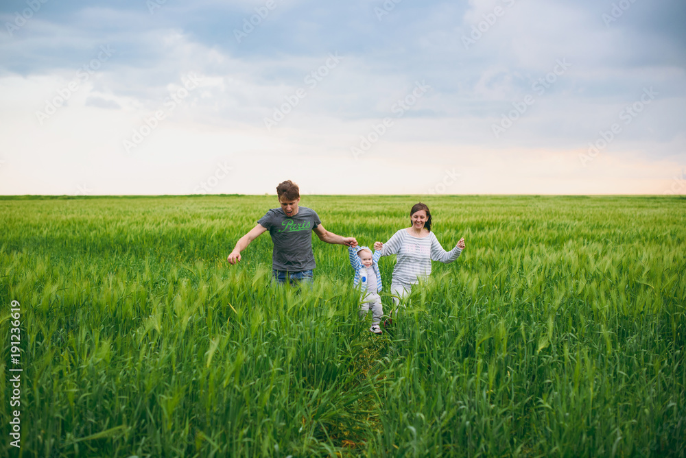 Joyful man, woman walk on green field background, rest, have fun, play, run with little cute child baby boy. Mother, father, little kid son. Family day 15 of may, love, parents, children concept. Joyful man, woman walk on green field background, rest, have fun, play, run with little cute child baby boy. Mother, father, little kid son. Family day 15 of may, love, parents, children concept.
