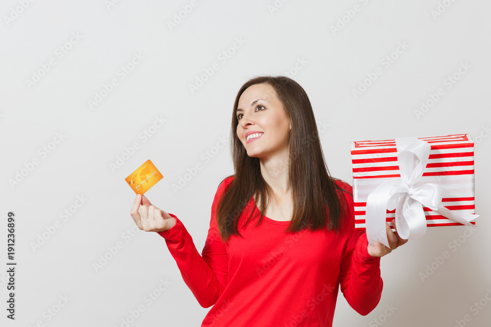 Beautiful woman holding credit card, red present box with gift isolated on white background. For advertisement. St. Valentine's Day, International Women's Day, Christmas, birthday, holiday concept. Beautiful woman holding credit card, red present box with gift isolated on white background. For advertisement. St. Valentine's Day, International Women's Day, Christmas, birthday, holiday concept.