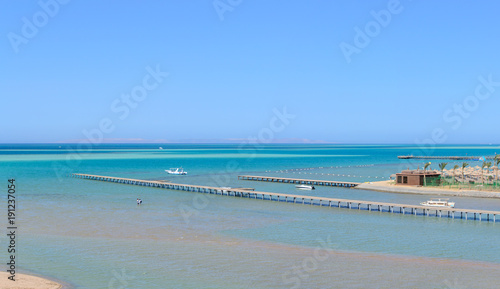 Beautiful paradise beach of the blue sea with a pier and a yacht panorama