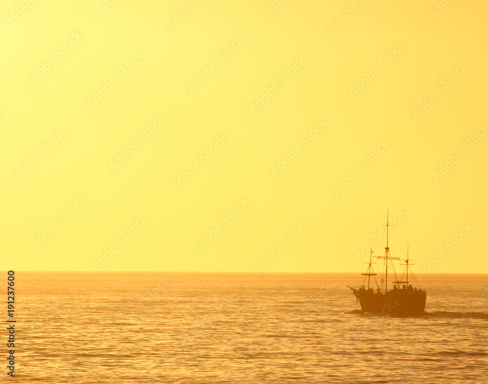 pirate ship sailing into golden sunset