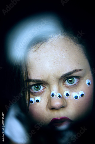 Portrait of girl with eyes on the face playing with a magnifying glass photo