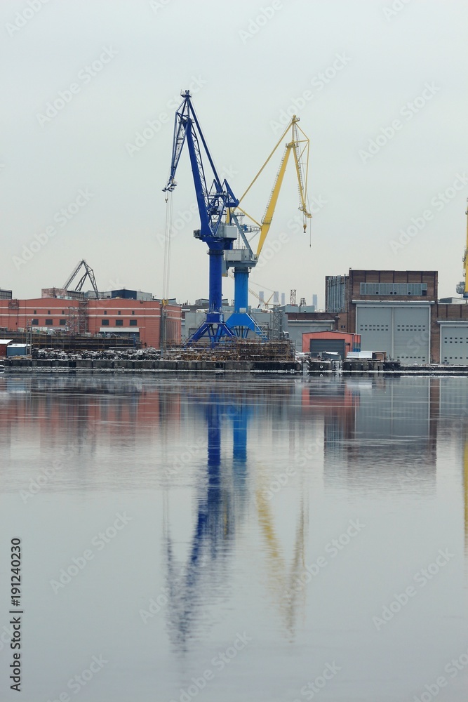 Port cranes on the shore with reflection in water