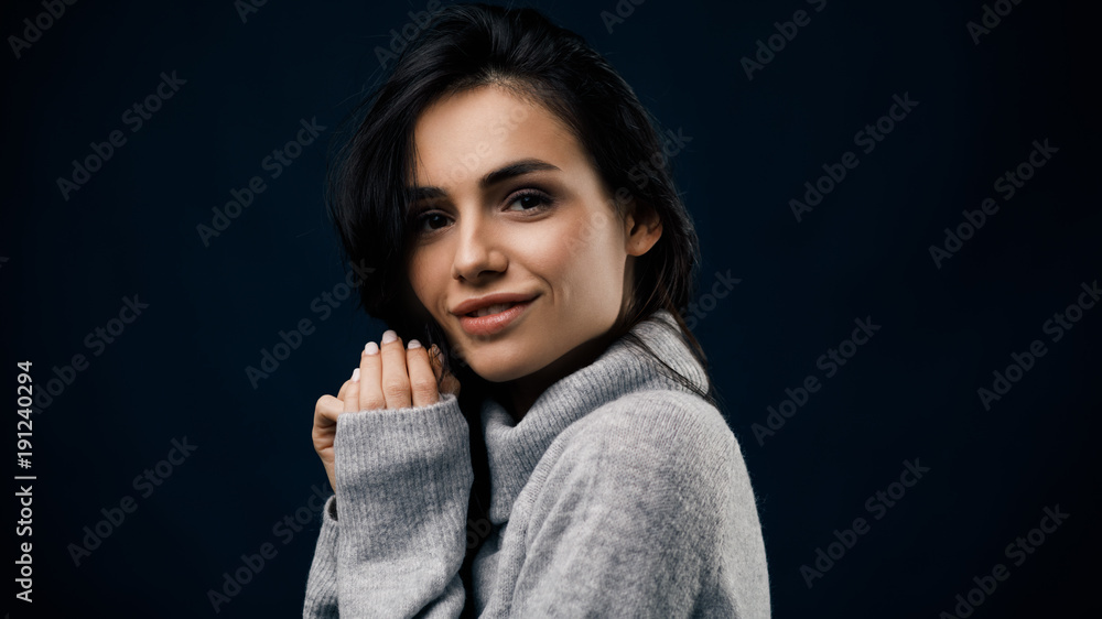 Young smiling brunette standing in studio with hands near her face Young smiling brunette standing in studio with hands near her face