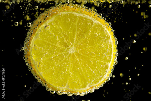Lemon slice in mineral water on the black background.