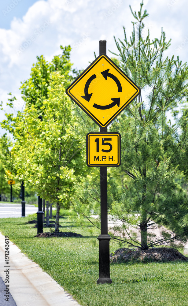 Vertical shot of a roundabout traffic sign with speed limit sign below
