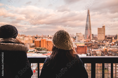 Canvas Print Two young tourist female friends looking at modern London skyline on day with cl