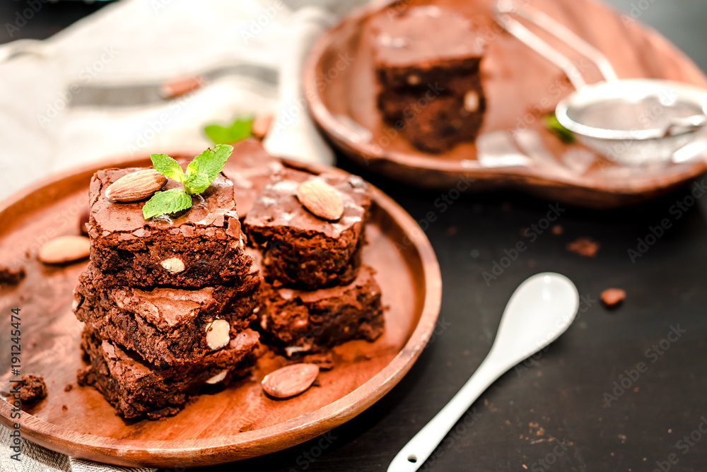 Delicious chocolate brownie with mint and almonds a wooden plate Delicious chocolate brownie with mint and almonds a wooden plate