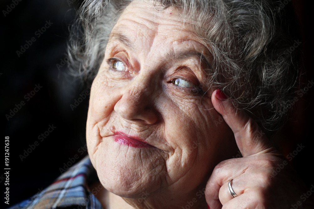Thoughtful and looking elderly woman face on a black Thoughtful and looking elderly woman face on a black