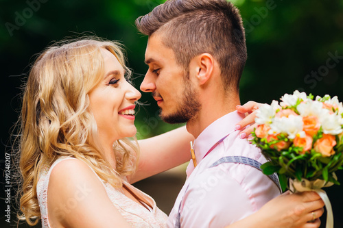 Close-up of a girl who holding a bouquet of flowers and hugging her boyfriend and smile