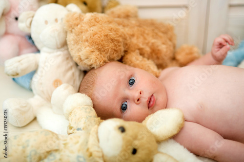 Baby lying by beige bunny. Newborn toddler with blue eyes © be free