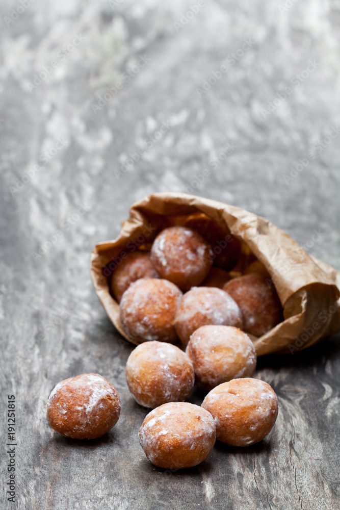 Obraz premium Mini doughnuts in paper bag on rustic wooden table
