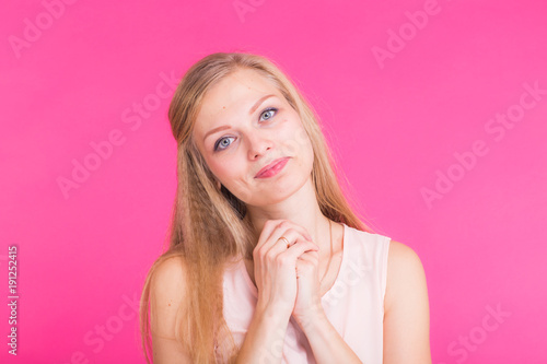 Pretty young woman smiling against a pink background.