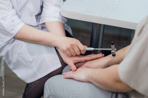 Cropped image of neurologist testing reflex on a female patient using a hammer