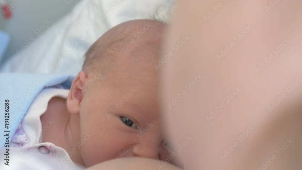 Close-up shot of newborn baby lying with mother on the bed under the blanket Close-up shot of newborn baby lying with mother on the bed under the blanket