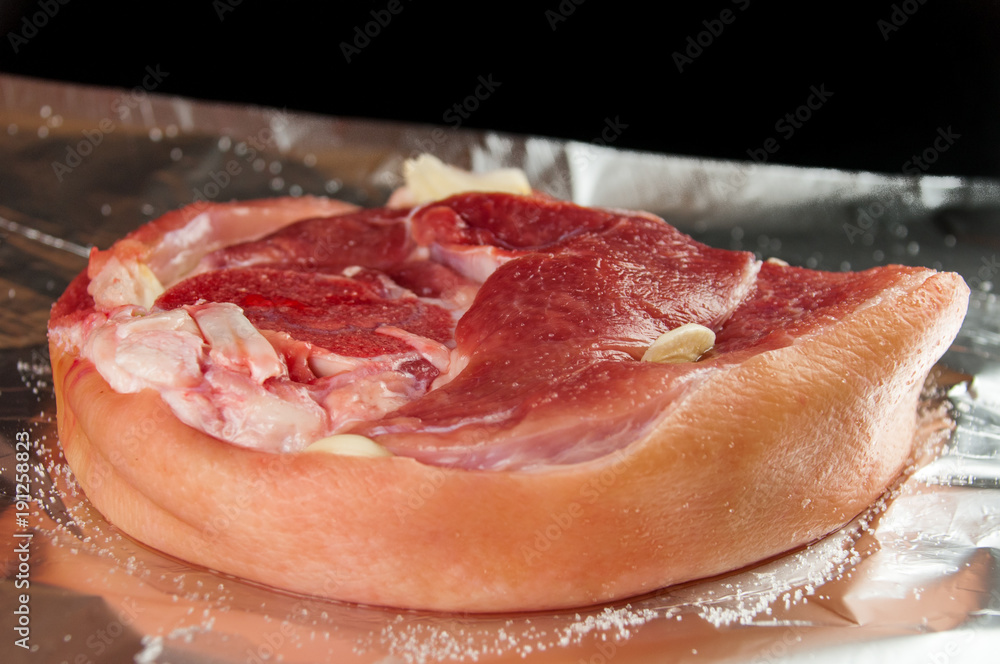 A raw piece of meat is sprinkled with sea salt, pepper. Foil for baking