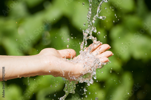 Woman washing hand outdoors. Natural drinking water in the palm. Young hands with water splash, selective focus