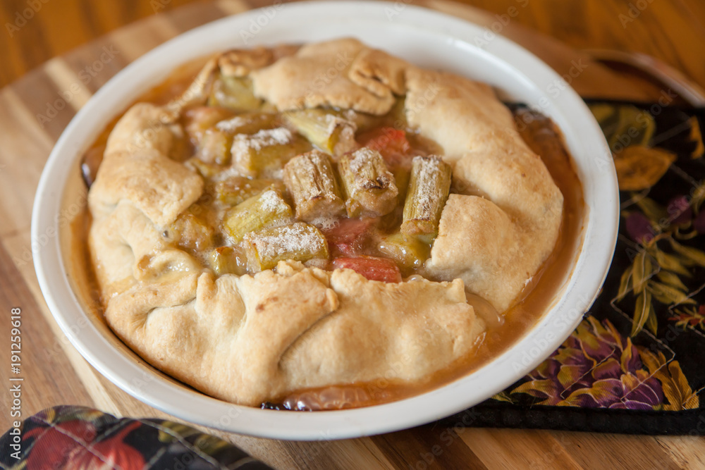Springtime Rhubarb Galette cooling on wooden board with potholders Springtime Rhubarb Galette cooling on wooden board with potholders