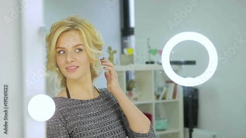 Cute blonde girl admires herself in the mirror in the beauty salon, touches her hair and smiles. Close up