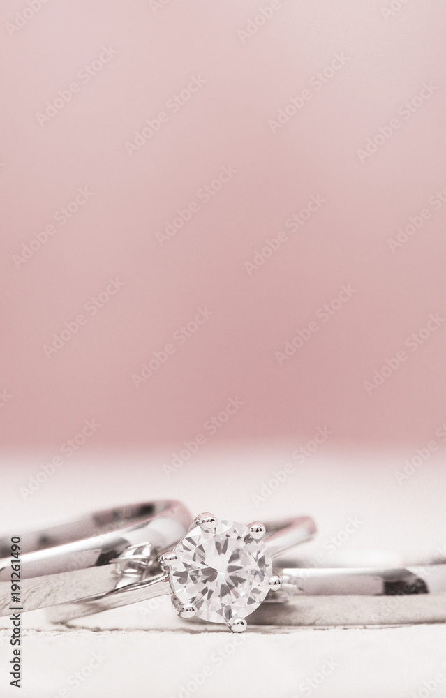 Macro View of Wedding Rings on a Wooden Table with Pink Background Macro View of Wedding Rings on a Wooden Table with Pink Background