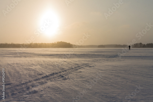 Ski track being covered by falling snow at a frozen lake.