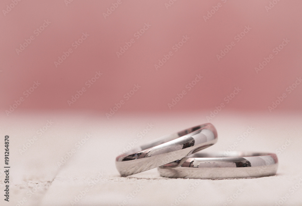 Macro View of Wedding Rings on a Wooden Table with Pink Background