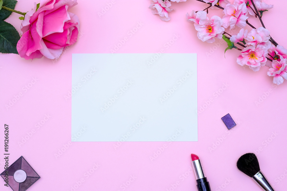 Set of makeup brushes, decorative cosmetics and flowers on pink colored composed background. Top view point, flat lay, space for text