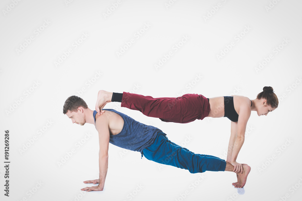 Naklejka premium Young athletic couple practicing acroyoga. Balancing in pair