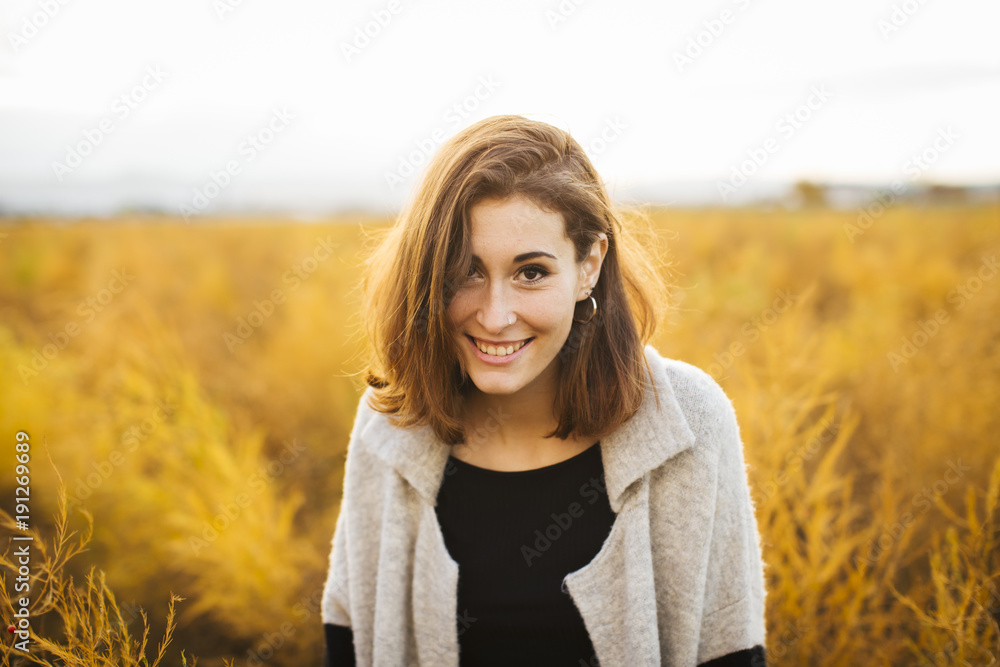 Young beautiful girl in the field. She wears a sweater and jeans. Yellow background. Young beautiful girl in the field. She wears a sweater and jeans. Yellow background.