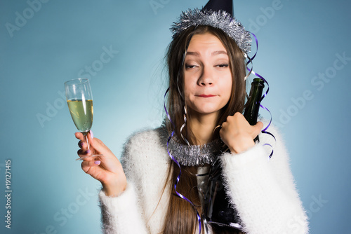 drunk woman in a festive cap holding champagne in hands photo