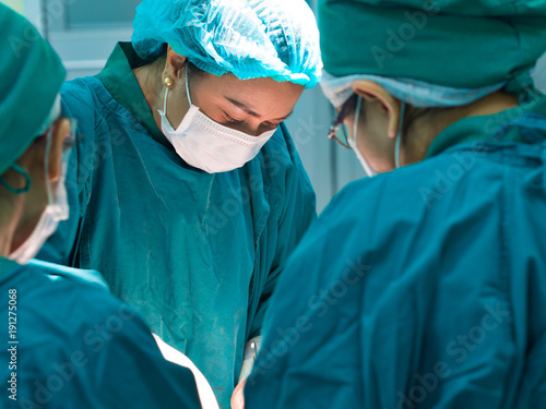 Portrait of Asian female doctor or surgeon doing operation in operating room at hospital for surgical treatment of acute bleeding patient in emergency condition 