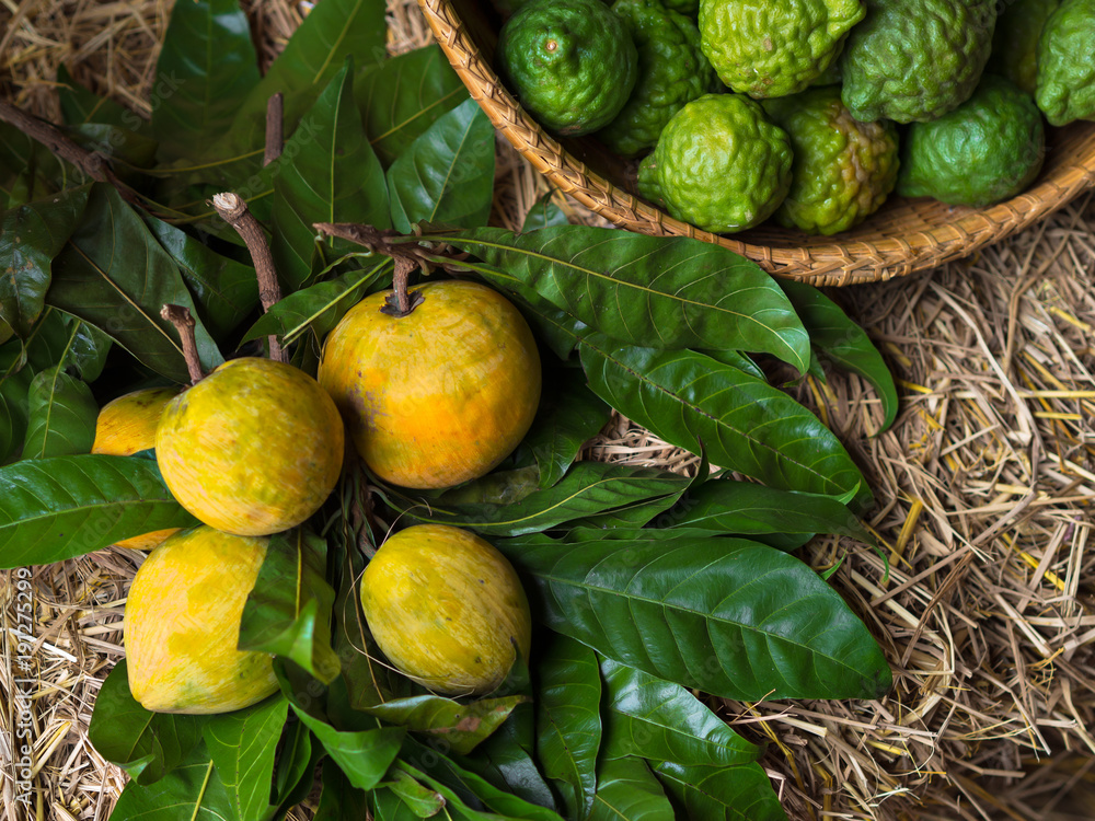 Obraz premium Yellow lemon, green bergamot and green leaves on wooden table and straw in an organic market for fresh, juicy, vitamin and healthy food and fruits 