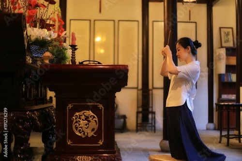 Photography a woman in traditional Chinese costume is praying on her knees with incenses in