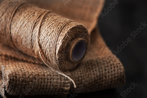 Natural jute twine roll, burlap on black background. Supplies and tools for handmade hobby leisure photo