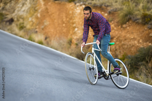 Fototapeta Naklejka Na Ścianę i Meble -  Cyclist man riding fixed gear sport bike in sunny day on a mountain road