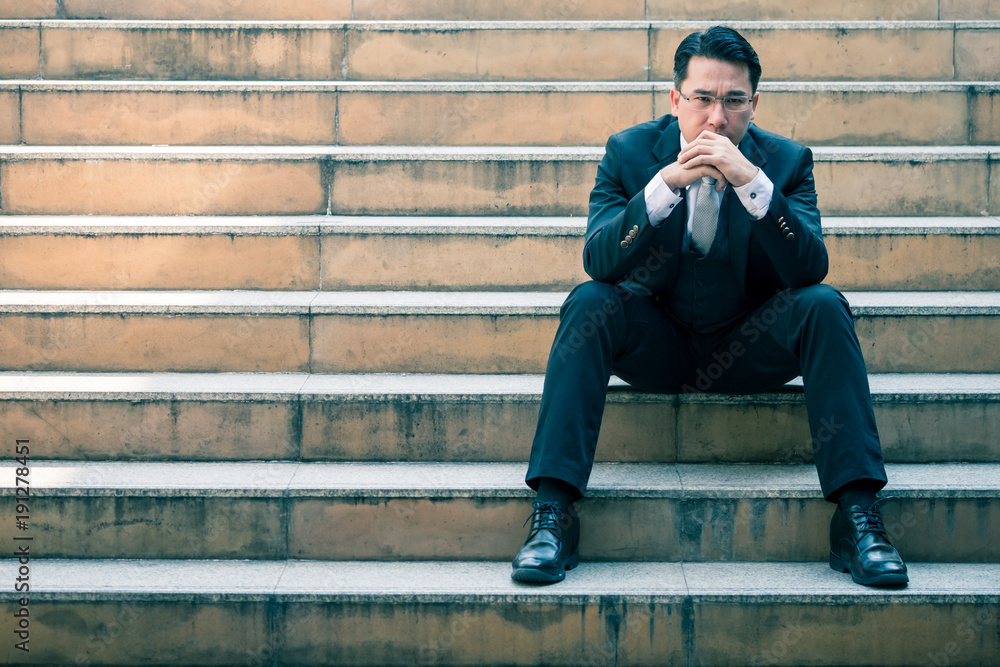 Portrait of Worried Asian businessman sitting on the city stairs. Copy space Portrait of Worried Asian businessman sitting on the city stairs. Copy space