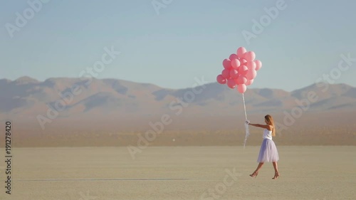 A girl with balloons walking in the desert Lake El Mirage. Slow motion. October 2017 photo