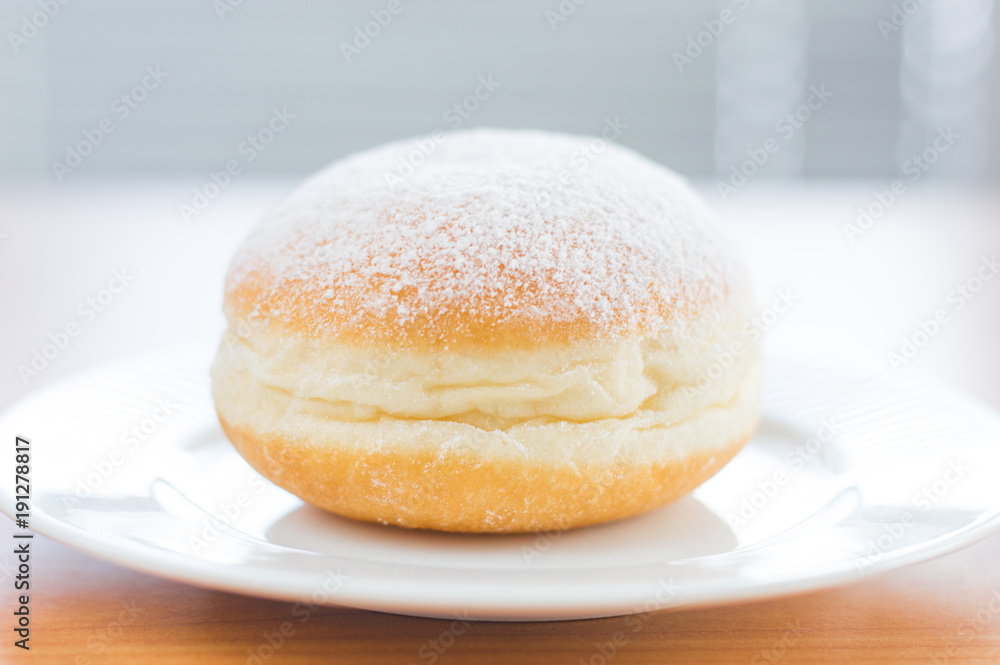 Traditional Polish Paczek with powdered sugar on white plate. Traditional Polish Paczek with powdered sugar on white plate.