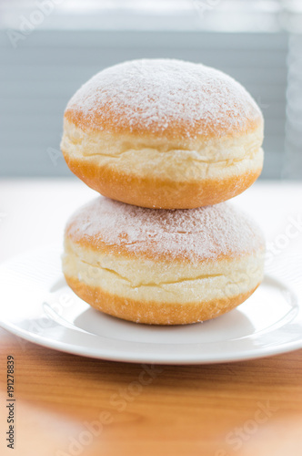 Two traditional Polish donuts (Paczek) with powdered sugar on white plate