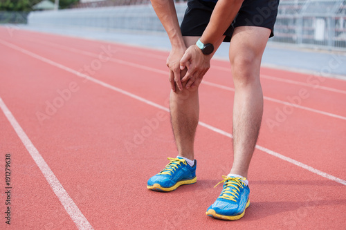 Young sport man with strong athletic legs holding knee with his hand in pain after